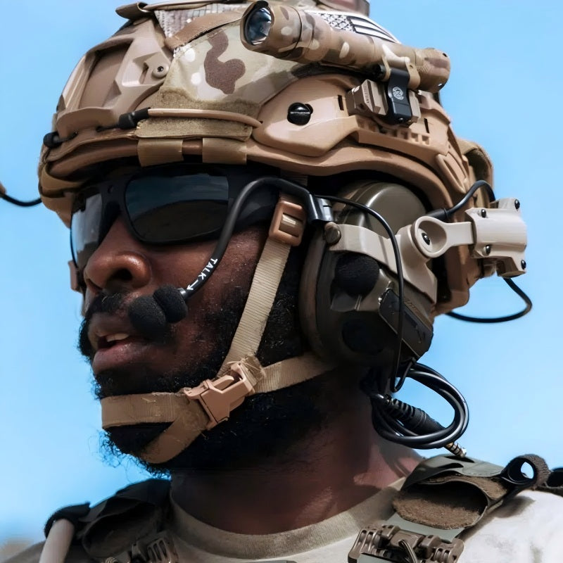 Lifestyle shot of Coyote Brown (CB) Level IIIA ACH high-cut ballistic helmet with MC camouflage cover, mounted tactical light, comms headset, and hook-and-loop patches, worn by a tactical operator